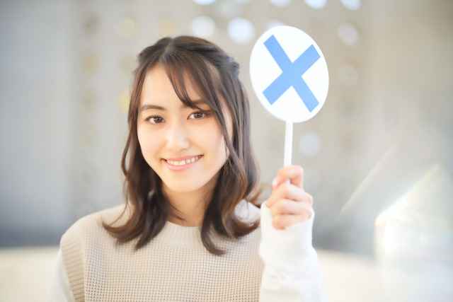 バツのプレートを持つ女性　写真